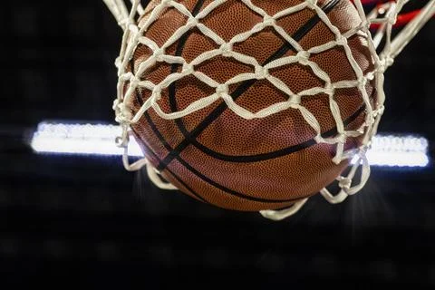 Looking up at the bottom of a basketball falling through the net with arena Foto stock