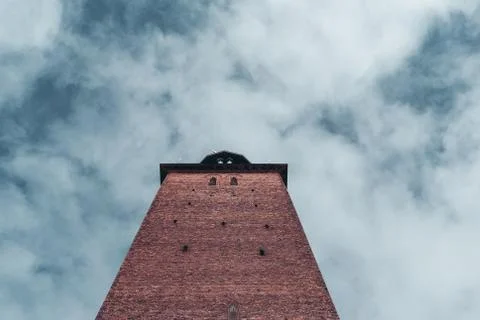 Looking up a brick tower on the sky with clouds Stock Photos