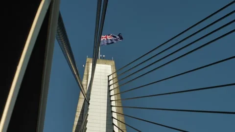 Looking up at cable-stayed bridge and Australian flag in the wind slomo Stock Footage 269613282