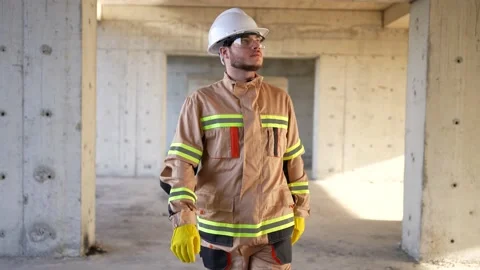 Looking at the camera male builder engineer in a white helmet walks through a Stock Footage 235187776
