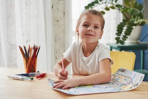Looking into the camera with satisfied look. Cute little girl in art school d Stock Photos