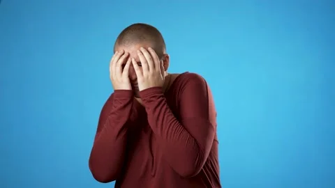 Looking at camera shocked surprised cover face with hands hiding, gender fluid Stock Footage 223579769