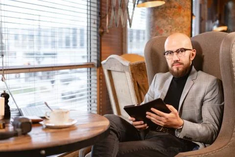 Looking into the camera. Young man with beard, wearing a suit in the glasses Stock Photos