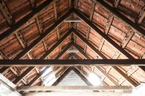 Looking up at the ceiling of an old barn with old roof tiles and wooden beams Stock Photos