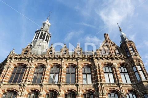 Looking up at colourful building facade with Zuiderkerk church steeple, blue sky Stock Photos