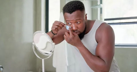 Looking down, African man picking eye patch, aligning and applying for care with Stock Footage 344334483