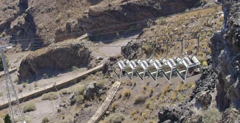 Looking down and following cable cars descending along cliff side slow motion Stock Footage 202251844