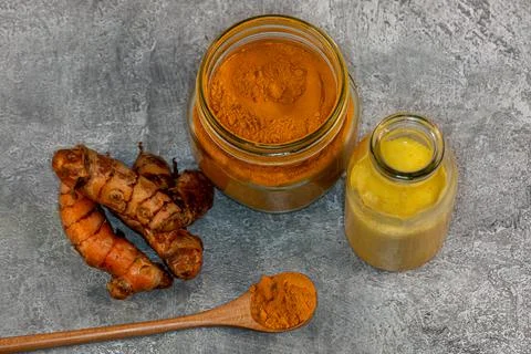 Looking down on an arrangement of turmeric root, powder and milk against a gr Foto stock