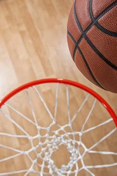 Looking down on a basketball almost in the net with arena wood floor in the Foto stock