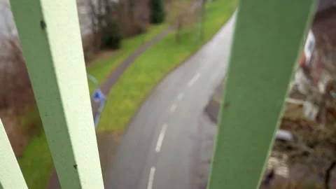 Looking down between metal bridge footbridge railings to road below Stock Footage 148828334