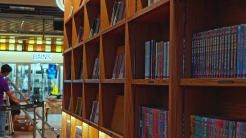 Looking down bookshelf in starfield library full of books with employee in Stock Footage 342814902