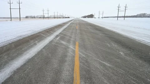 Looking down the centreline of a two lane paved road with blizzard snow blowing  Stock Footage 221572694