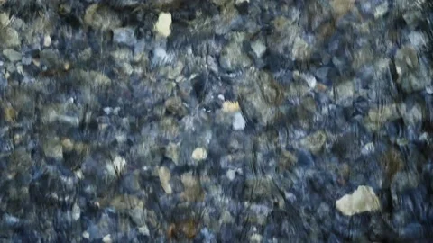 Looking down on a clear fast-moving river with rocks in many shades of gray  Stock Footage 142241347