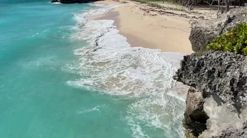  looking down a cliff to a beach, while waves hitting the cliff and the beach Stock Footage 321406425