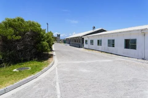 Looking down a cobbled road on Robben Island, past former prison buildings Stockfoto's