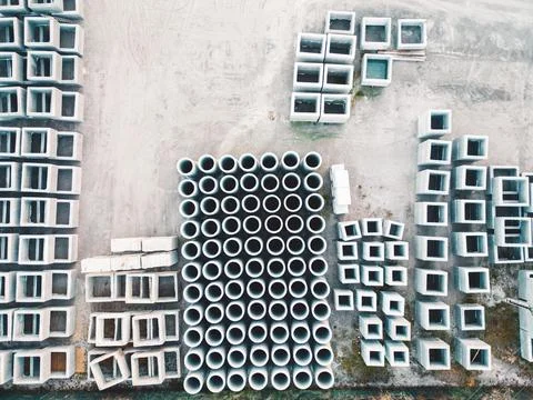 Looking down at concrete blocks and pipes neatly stacked in rows on the ground Stock Photos