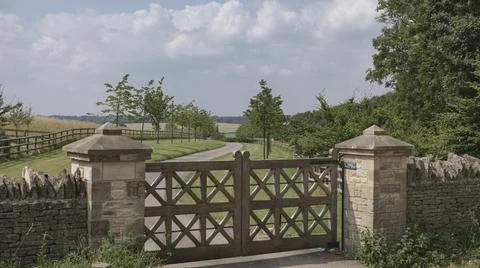 Looking down a driveway through ornate wooden gates Foto stock
