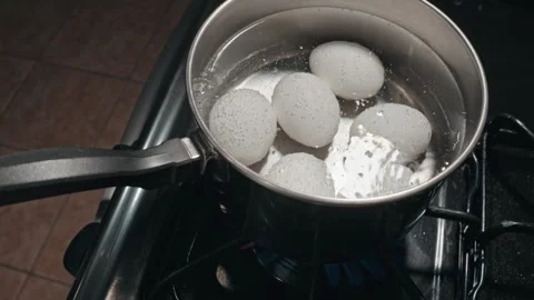 Looking down at eggs in a pan beginning to be hard boiled Stock Footage 318630638