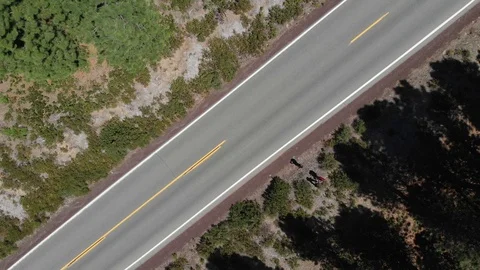 Looking down at a empty road, going up, turning clockwise revealing forest. Stock Footage 116015490