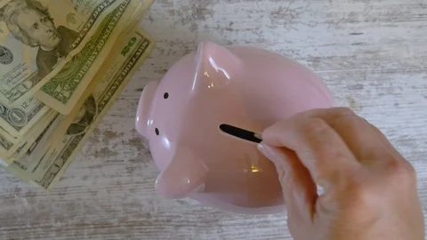 Looking down at hands putting coins into a piggy bank Stock Footage 121133660