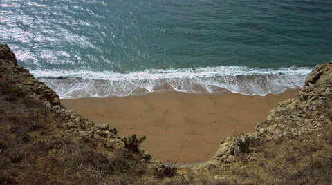 Looking down from high cliffs onto sandy beach and sea with gentle waves - 4K Stock-Footage 47857281
