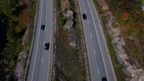 Looking down on highway tilting up to wide shot of forest. Early autumn colors Stock Footage 251565040