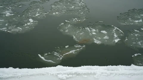 Looking down at ice chunks flowing by in River Stock Footage 327716469