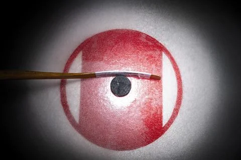 Looking down on an ice hockey stick with puck sitting on the Face Off circle Foto stock