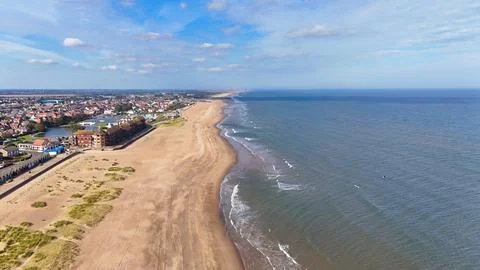 Looking down a long golden beach with the waves lapping the shoreline Stock Photos