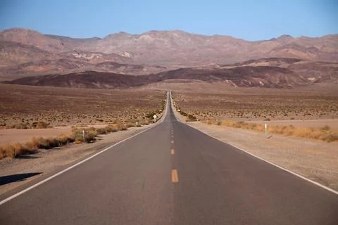 Looking down the middle of a long straight desert road with no one in site fo Foto stock