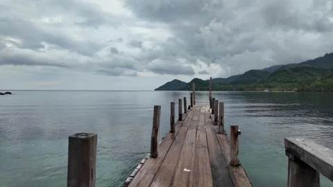 Looking Down Old Wooden Dock Over Calm Sea Toward Island Stock Footage 268705752