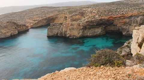 Looking down over edge of rocky island at a clear blue sea Stock Footage 37531885