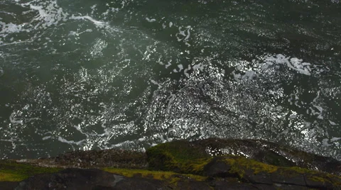 Looking down on Pacific waves surging around a mossy rock Stock Footage 59146082