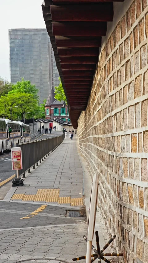 Looking down pathway at deoksugung stone wall path in seoul street with brick Vídeo Stock 345021255