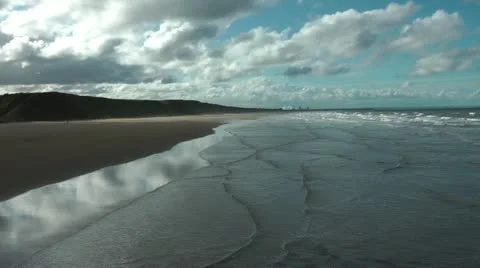 Looking down from pier as tide comes in to empty beach Stock Footage 12561389