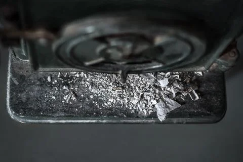 Looking down on rustic, grey ash pile in front of rough, black iron oven Stock Photos