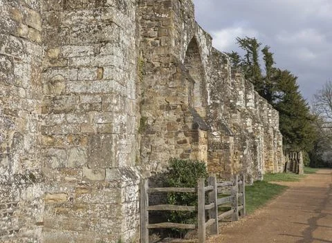 Looking down a sandy pathway along a wall and wooden fence Stock Photos