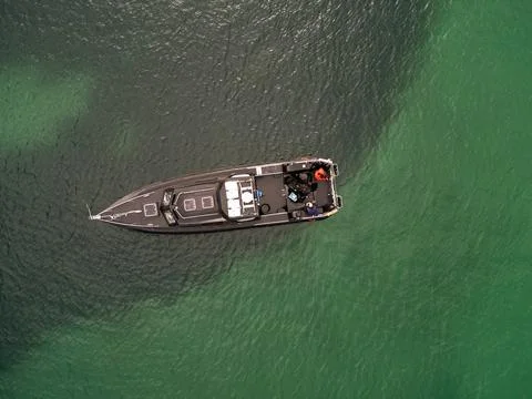 Looking down on a small black boat on the sea near the Isle of Coll, Scotland Фото