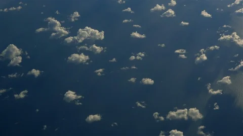 Looking down on small white clouds above a blue ocean Video stock 98556992