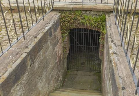 Looking down some old stone steps at a gate made of metal Stock Photos