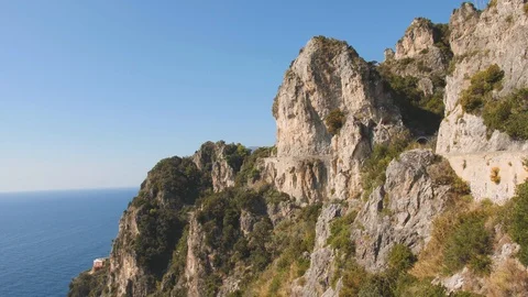 Looking down from steep coastal cliff on blue sea. Rocks on sunny day. Salerno Stock-Footage 100743475
