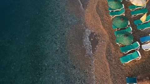 Looking down to sunbeds and umbrellas at a beach of a turquoise sea Stock Footage 115267186