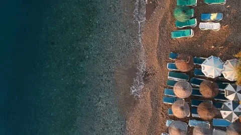 Looking down to sunbeds and umbrellas at a beach of a turquoise sea Stock Footage 115267297
