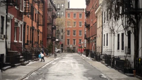 Looking down a thin urban street at snow covered stoops on a cold brisk Stock Footage 94605202