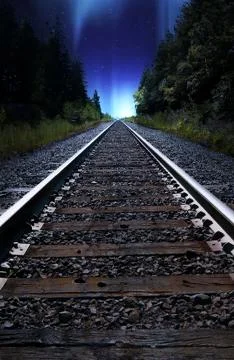 Looking down train tracks at night with Northern Lights in Sky Stock Photos
