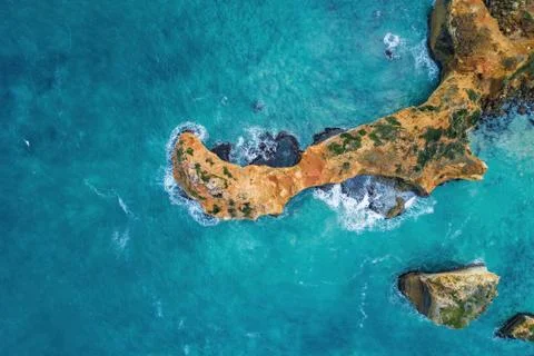 Looking down at turquoise ocean waves breaking over rocks - aerial view Stock Photos