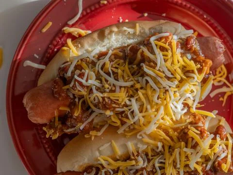 Looking down at two chili dogs on a red plate Stock Photos