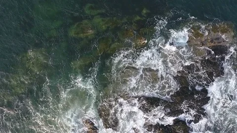Looking down on waves crashing on rocks Stock Footage 84745937