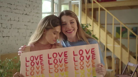 Looking to each other, two handsome young girls are standing in the studio and Stock Footage 172772996