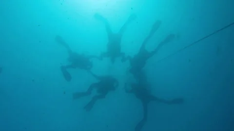 Looking up at five descending scuba divers holding hands like skydivers Stock Footage 48581507